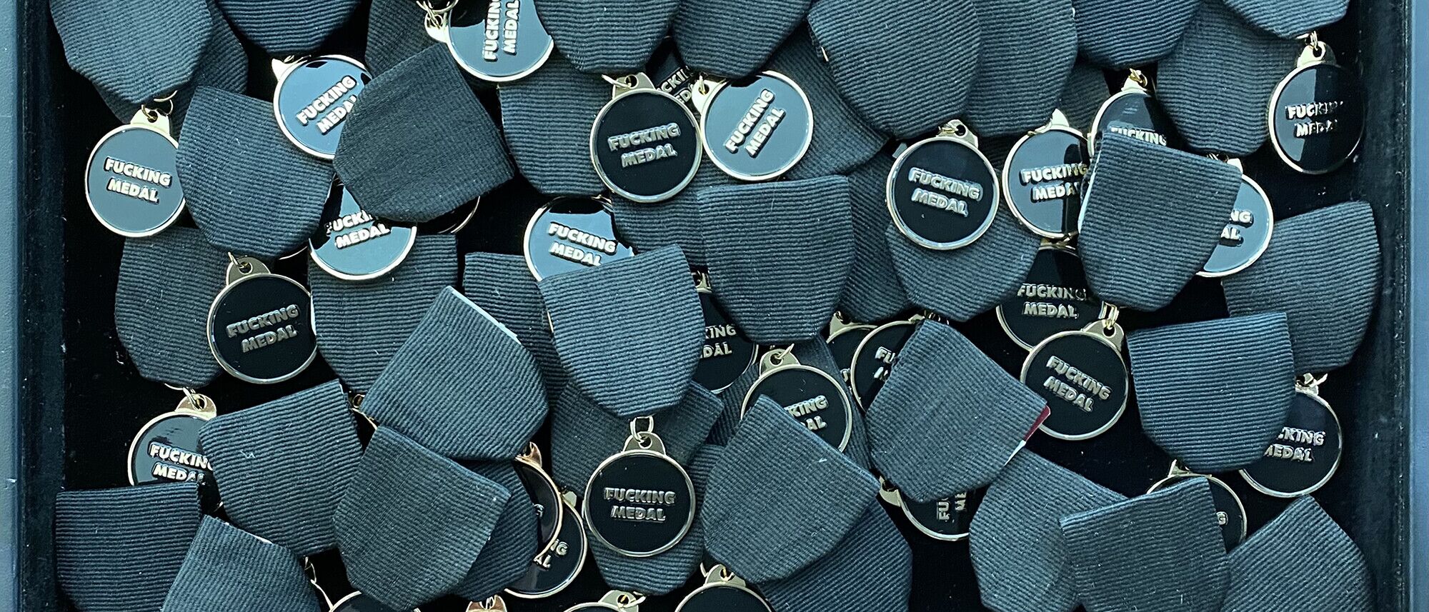 A tray of Fucking Medals, gold on black enamel